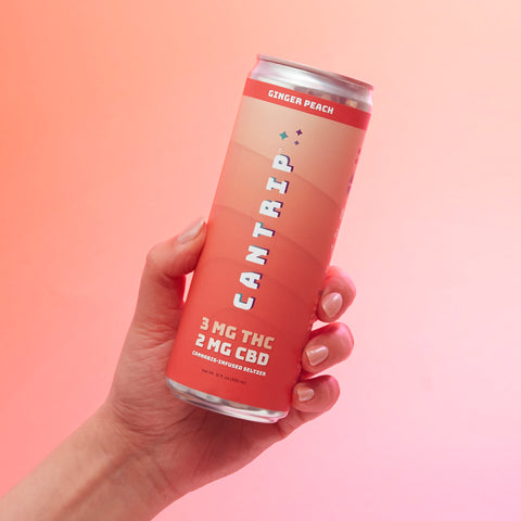 Lifestyle image of a hand holding a red CBD seltzer, orange and pink background