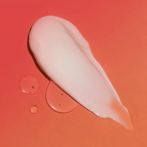 Lifestyle image of a topical smear on a surface, orange and pink background