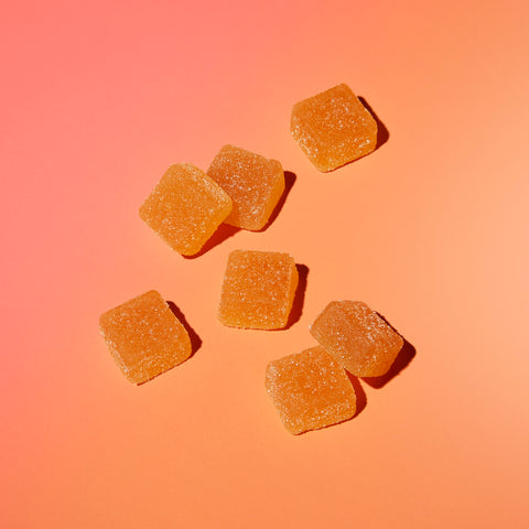 Lifestyle image of gummies on a surface, orange background