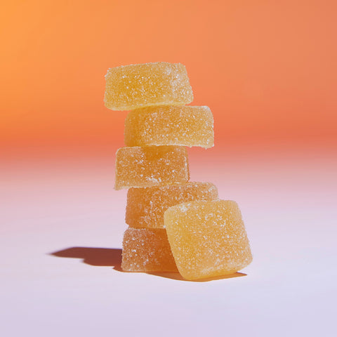 Lifestyle image of a stack of CBD gummies, orange and pink background