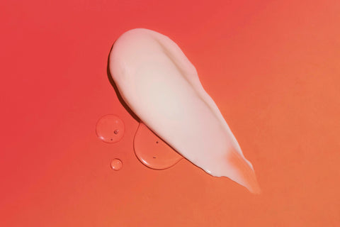 Lifestyle image of a topical smear on a surface, orange and pink background